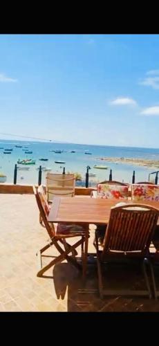 una mesa de madera y sillas junto a la playa en Bouznika pied dans l'eau, en Kasba Bou Hamira