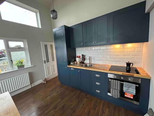 a kitchen with dark blue cabinets and a sink at Glenogue Farm in Gorey