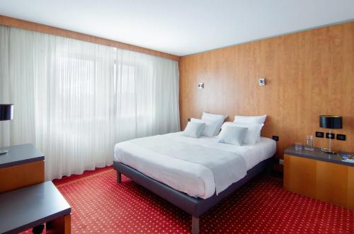 a hotel room with a large bed with white sheets at CERISE Bordeaux Mérignac Aéroport in Mérignac