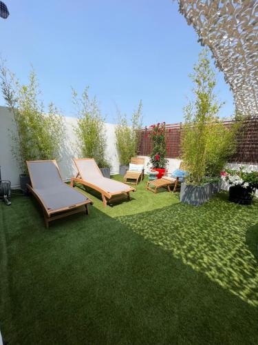 a yard with three lounge chairs on the grass at L'Avant Scène Meublé 5 étoiles Parking Gratuit Jacuzzi in Avignon