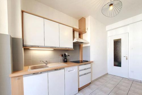 une cuisine avec des armoires blanches et un évier dans l'établissement CHIC - Proche Hypercentre - Rénové - Lumineux, à Strasbourg