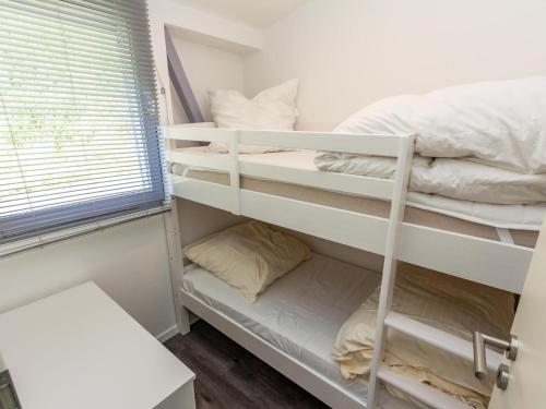 ein Schlafzimmer mit weißen Etagenbetten und einem Fenster in der Unterkunft Bungalow in Waxweiler in the southern Eifel in Waxweiler