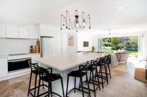 a kitchen with a large white table and black chairs at Bawley Point Oasis - Steps from Bawley Beach in Bawley Point