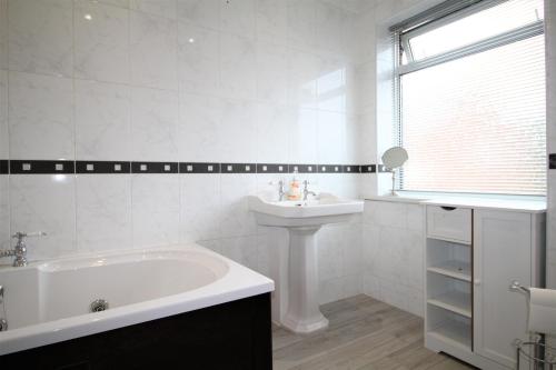 a white bathroom with a tub and a sink at Whitley Bay - Sleeps 6 - Refurbished Throughout - Fast Wifi - Dogs Welcome in Whitley Bay