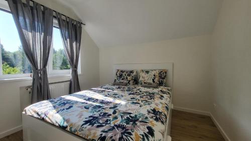 1 Schlafzimmer mit einem Bett mit einer Blumendecke und einem Fenster in der Unterkunft Villa Saulkrasti Balta Kapa White Dunes in Saulkrasti