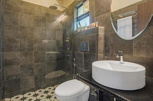 ein Badezimmer mit einem Waschbecken, einem WC und einem Spiegel in der Unterkunft StayVista at Mawi Summers in Arambol