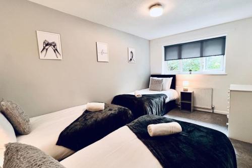 a bedroom with three beds and a window at Urban Bliss Stylish Townhouse with Free Parking for a Convenient City Stay in Liverpool