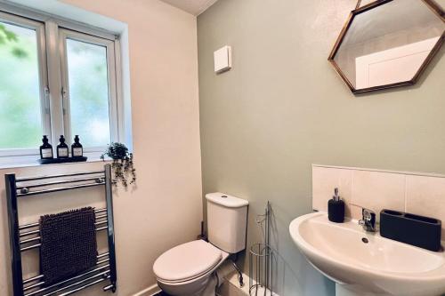 a white bathroom with a toilet and a sink at Urban Bliss Stylish Townhouse with Free Parking for a Convenient City Stay in Liverpool