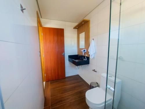 a bathroom with a toilet and a glass door at Pousada Ametista - Penha, SC - 1,5 km do Parque Beto Carrero World in Penha