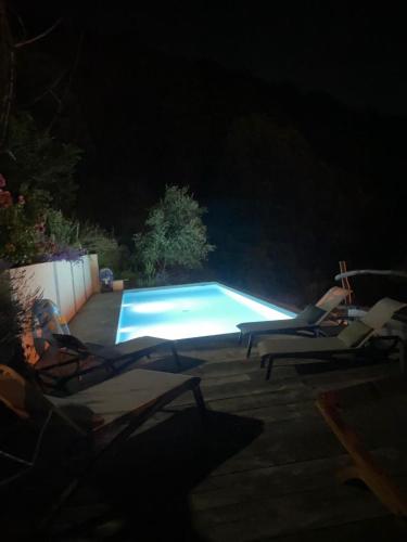 a swimming pool at night with two lounge chairs next to it at LES CABANES DE LUTINA in Poggio-Marinaccio