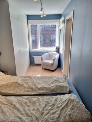 a bedroom with a bed and a chair and a window at Hele Leiligheten, Grünerløkka in Oslo