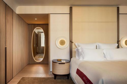 um quarto de hotel com uma cama e um espelho em Bulgari Hotel Roma em Roma