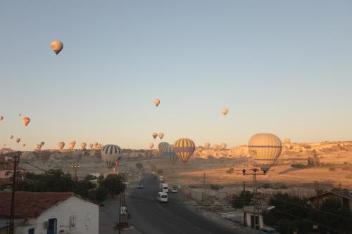 a group of hot air balloons flying over a road at Heritage Cave Inn Hotel in Avanos