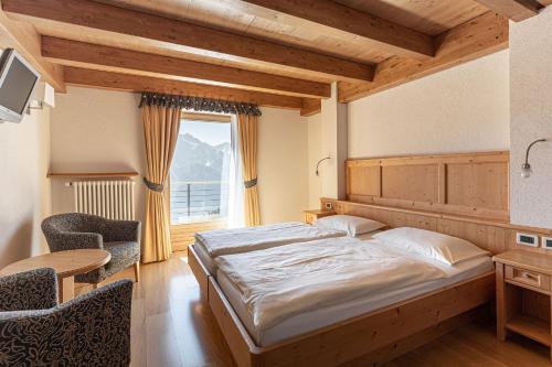 コンメッツァドゥーラにあるHotel Rifugio Solanderのベッドルーム1室(ベッド1台、テーブル、窓付)