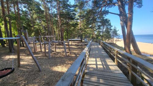 a wooden pathway to the beach with trees and the ocean at Villa Saulkrasti Balta Kapa White Dunes in Saulkrasti