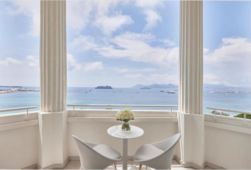 a table and chairs in a room with a view of the ocean at Hôtel Martinez, in The Unbound Collection by Hyatt in Cannes