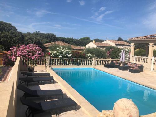 - une piscine avec des chaises longues et des fleurs dans la cour dans l'établissement L'ensoleillade du Pont du Gard, à Vers-Pont-du-Gard