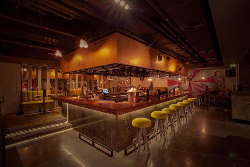 a bar in a restaurant with yellow stools at Sheraton Grand Hotel, Dubai in Dubai