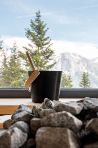 a cup with a wooden spoon sitting on a table next to a window at Hotel Rifugio Solander in Commezzadura