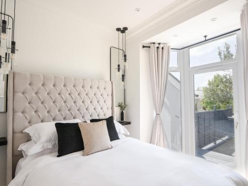 a white bedroom with a large bed and a window at Fore Street House - Apartment 2 in Seaton