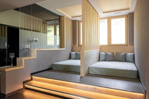 two beds in a room with two windows at Hotel Rifugio Solander in Commezzadura