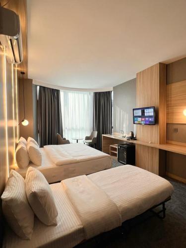 a hotel room with two beds and a flat screen tv at Royal Mass Airport Business Hotel in Arnavutköy