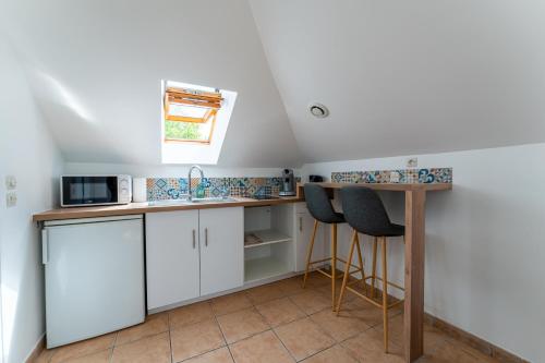 une cuisine avec des armoires blanches et un comptoir avec des tabourets dans l'établissement Poissy - Ma Résidence Privée, à Poissy