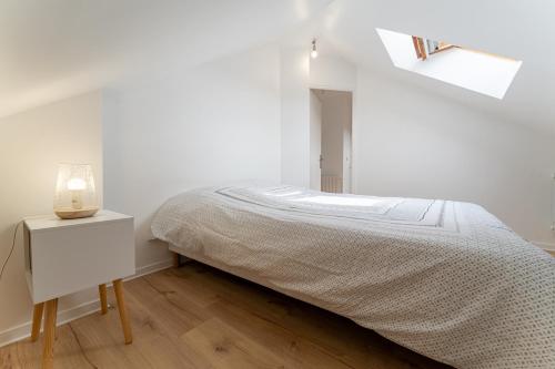 a white bedroom with a bed and a night stand at Poissy - Ma Résidence Privée in Poissy