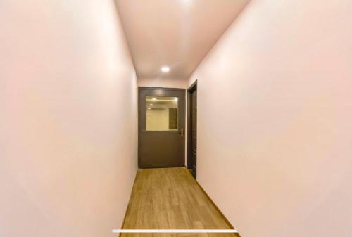 a hallway with a black door and a wooden floor at FabExpress Heera Holiday Inn - Nr Eden Garden Stadium in Kolkata
