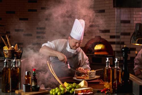 a chef preparing food on a plate in a kitchen at Holiday Inn & Suites - Dubai Science Park by IHG in Dubai