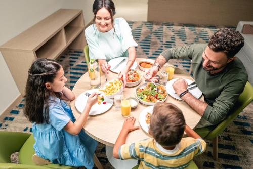 a group of people sitting around a table eating food at Holiday Inn & Suites - Dubai Science Park by IHG in Dubai