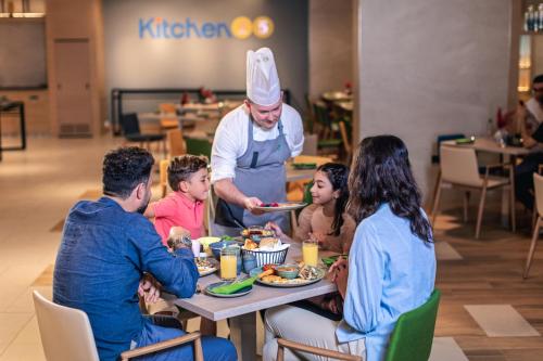 a group of people sitting around a table eating food at Holiday Inn & Suites - Dubai Science Park by IHG in Dubai