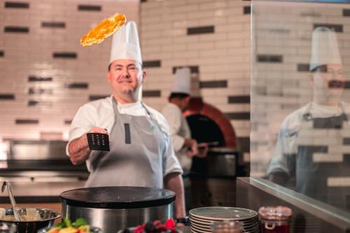 a chef is standing in a kitchen preparing food at Holiday Inn & Suites - Dubai Science Park by IHG in Dubai