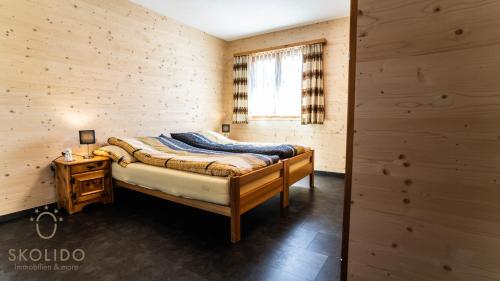 a bedroom with a bed in a wooden wall at Ferienwohnung Chalet Bortelhorn, Rosswald in Termen
