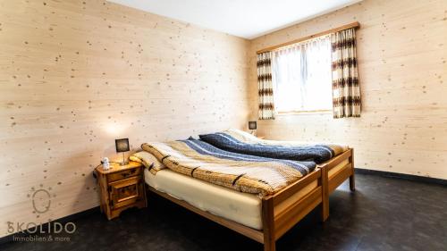 a bedroom with a bed in a wooden wall at Ferienwohnung Chalet Bortelhorn in Termen