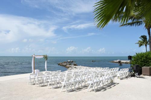 a row of white chairs sitting on the beach at Courtyard by Marriott Faro Blanco Resort in Marathon