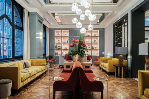 un hall avec des canapés jaunes et une table avec des fleurs dans l'établissement LUME Boutique Hotel, Autograph Collection, à Francfort-sur-le-Main