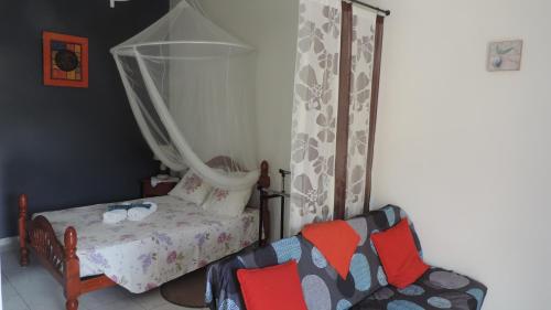 een kleine slaapkamer met een bed en een stoel bij VILLA CREOLE in Gourbeyre