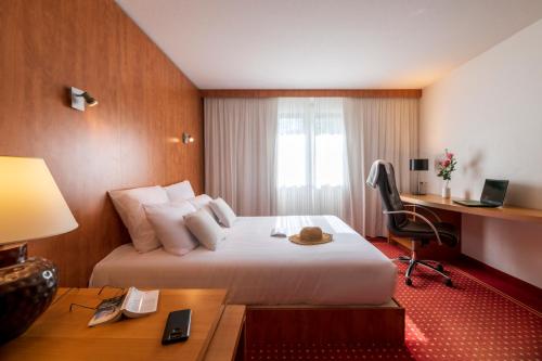 ein Hotelzimmer mit einem großen Bett und einem Schreibtisch in der Unterkunft CERISE Bordeaux Mérignac Aéroport in Mérignac