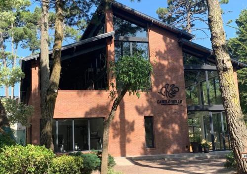 un gran edificio de ladrillo con árboles delante de él en Carilo Hills by bund en Cariló