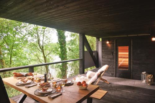 a table on the deck of a tree house at Hutstuf The Eagle & Private Outdoor Spa in La-Roche-en-Ardenne