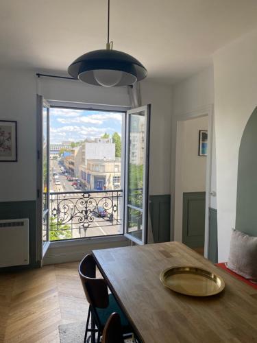 une salle à manger avec une table et une grande fenêtre dans l'établissement 3 pièces très proche Stade de France, Adidas Arena, à Saint-Denis