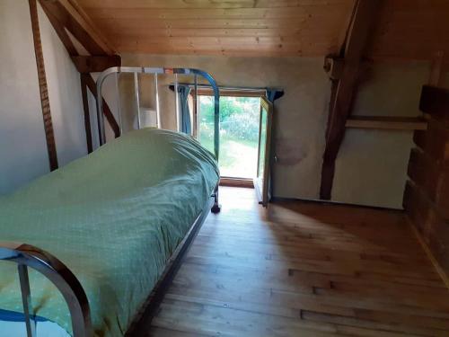 a bed in a room with a wooden floor at La maison parfumée in La Valade