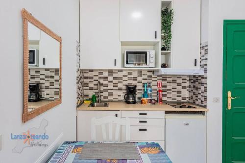 a kitchen with white cabinets and a green door at Lima Vivienda Vacacional in Puerto del Carmen