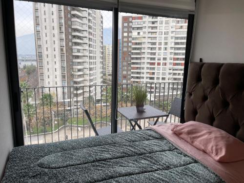 um quarto com uma cama e uma grande janela em Paso mall vespucio em Santiago