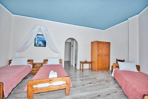 una camera con tre letti e un soffitto blu di Villa Nikos Karamolegkos Kamari a Kamari