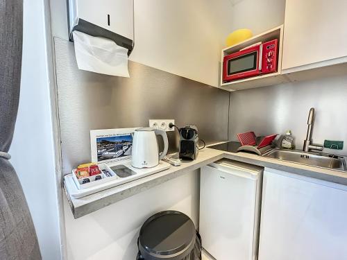 une petite cuisine avec un évier et un micro-ondes dans l'établissement Sweet Home Marceau 6 studios hyper centre proche de la mer et du palais, à Cannes