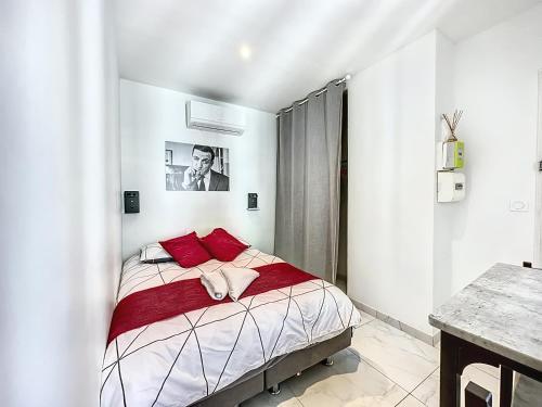 - une chambre blanche avec un lit et des oreillers rouges dans l'établissement Sweet Home Marceau 6 studios hyper centre proche de la mer et du palais, à Cannes
