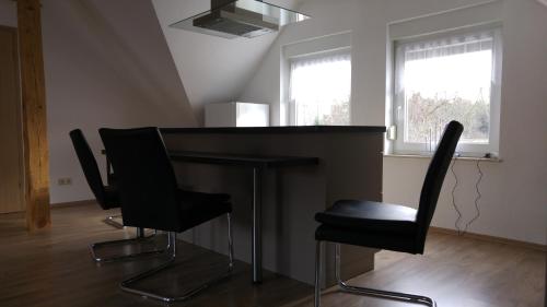 een keuken met een tafel en twee zwarte stoelen bij BogottHof in Elsterheide