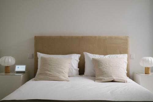 a bed with white sheets and pillows and two lamps at Aldoar House in Porto